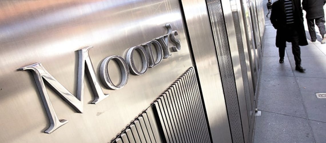 Pedestrians walk past the Moody's Investors Service Inc. logo displayed outside of the company's headquarters in New York, U.S., on Tuesday, Feb. 21, 2012. Moody's Corp. is a credit rating, research, and risk analysis firm. Photographer: Scott Eells/Bloomberg