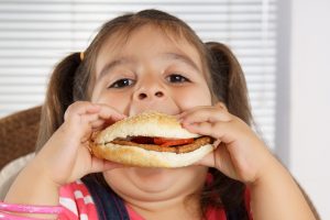 little caucasian girl eating burger