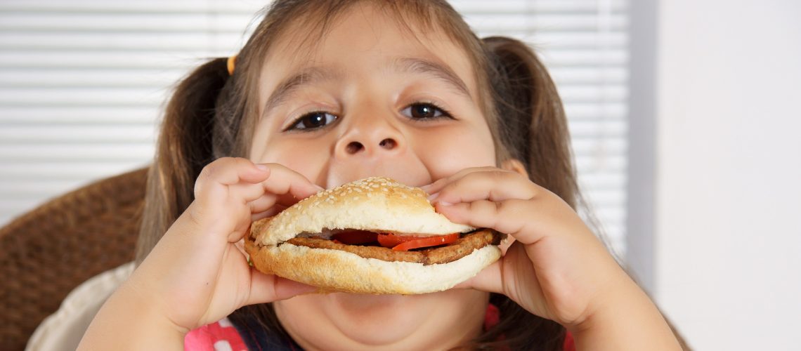 little caucasian girl eating burger