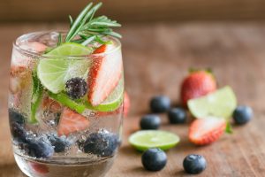 Infused water made from blueberry strawberry and lemon in sparkling mineral water look so freshness and healthy. Mixed fruit mojito on wood table with copy space. Summer refreshing drink concept. Ice blueberry soda in clear glass for summer.