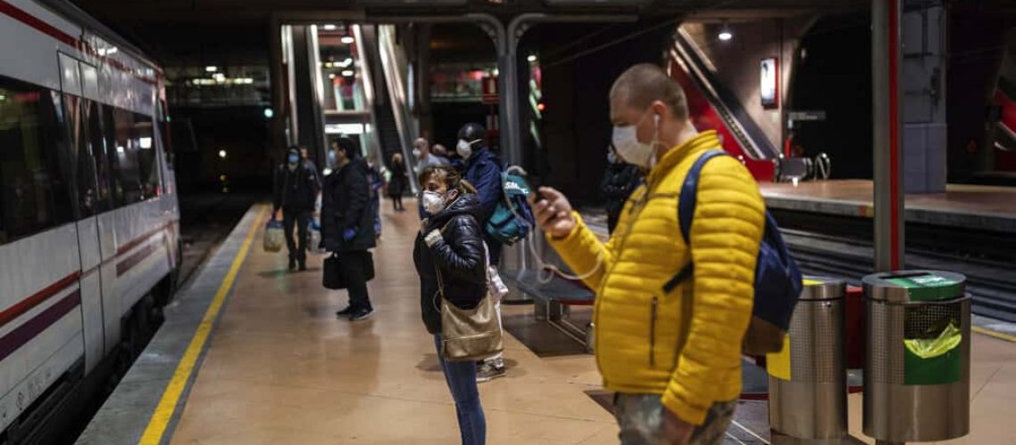 Commuters wearing face masks to protect against coronavirus at the platform of Atocha train station in Madrid, Spain, Monday, April 13, 2020. Confronting both a public health emergency and long-term economic injury, Spain is cautiously re-starting some business activity to emerge from the nationwide near-total freeze that helped slow the country's grim coronavirus outbreak. The new coronavirus causes mild or moderate symptoms for most people, but for some, especially older adults and people with existing health problems, it can cause more severe illness or death. (AP Photo/Bernat Armangue)