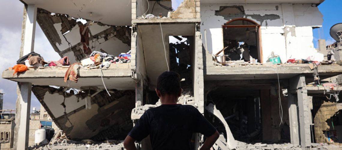 TOPSHOT - A Palestinian youth stand in front of a destroyed building following Israeli bombardment of Rafah's Tal al-Sultan district in the southern Gaza Strip on May 7, 2024. The Israeli army said it took "operational control" of the Palestinian side of the Rafah border crossing between Gaza and Egypt on May 7 and that troops were scanning the area. (Photo by AFP) (Photo by -/AFP via Getty Images)